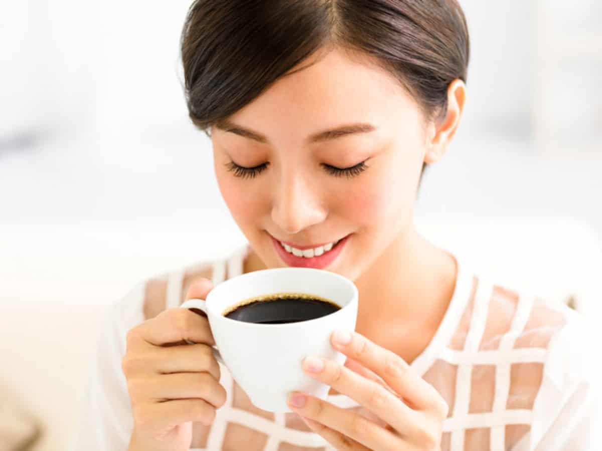 girl smelling her coffee while smiling