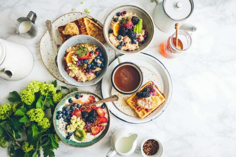 A healthy breakfast containing fruits, bread, waffle and coffee.