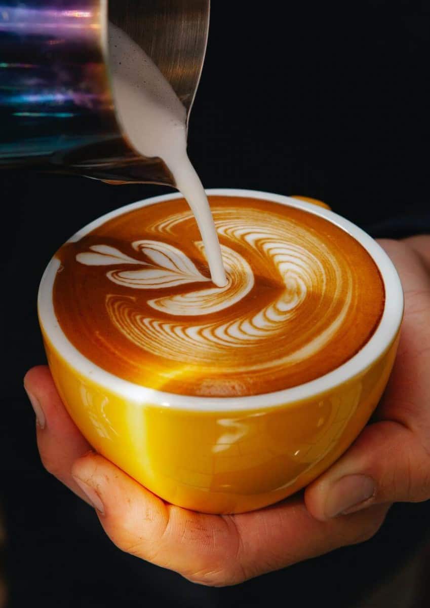 Cream being poured in a cup of coffee