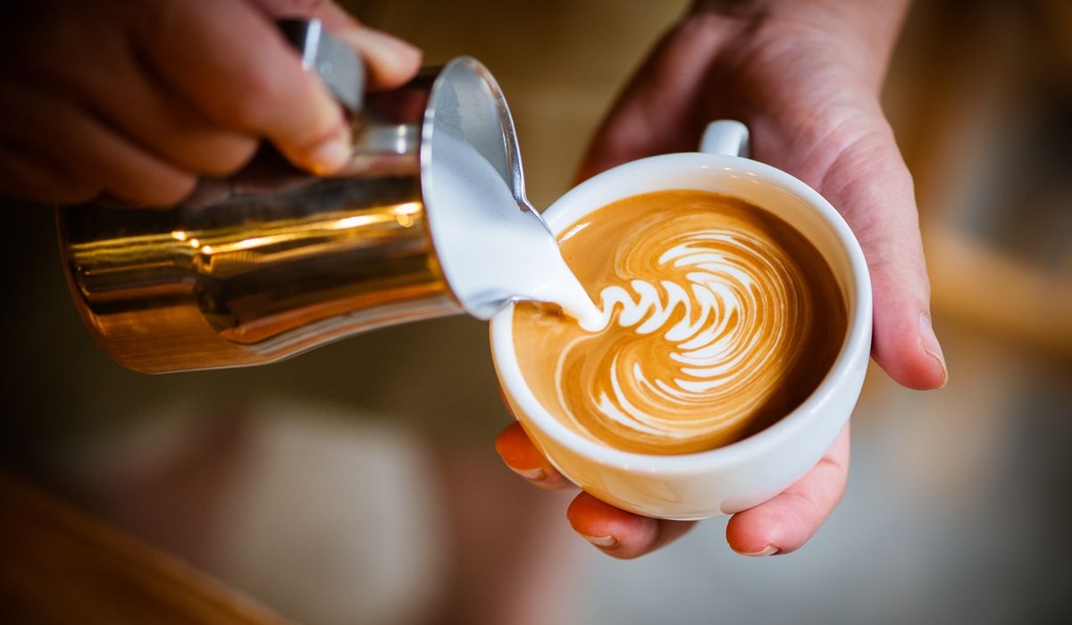 creamer being poured into a cup of coffee