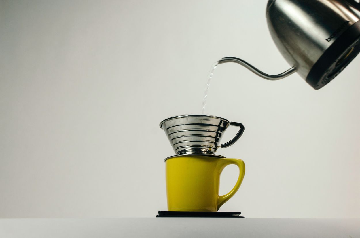 a person brewing a cup of coffee