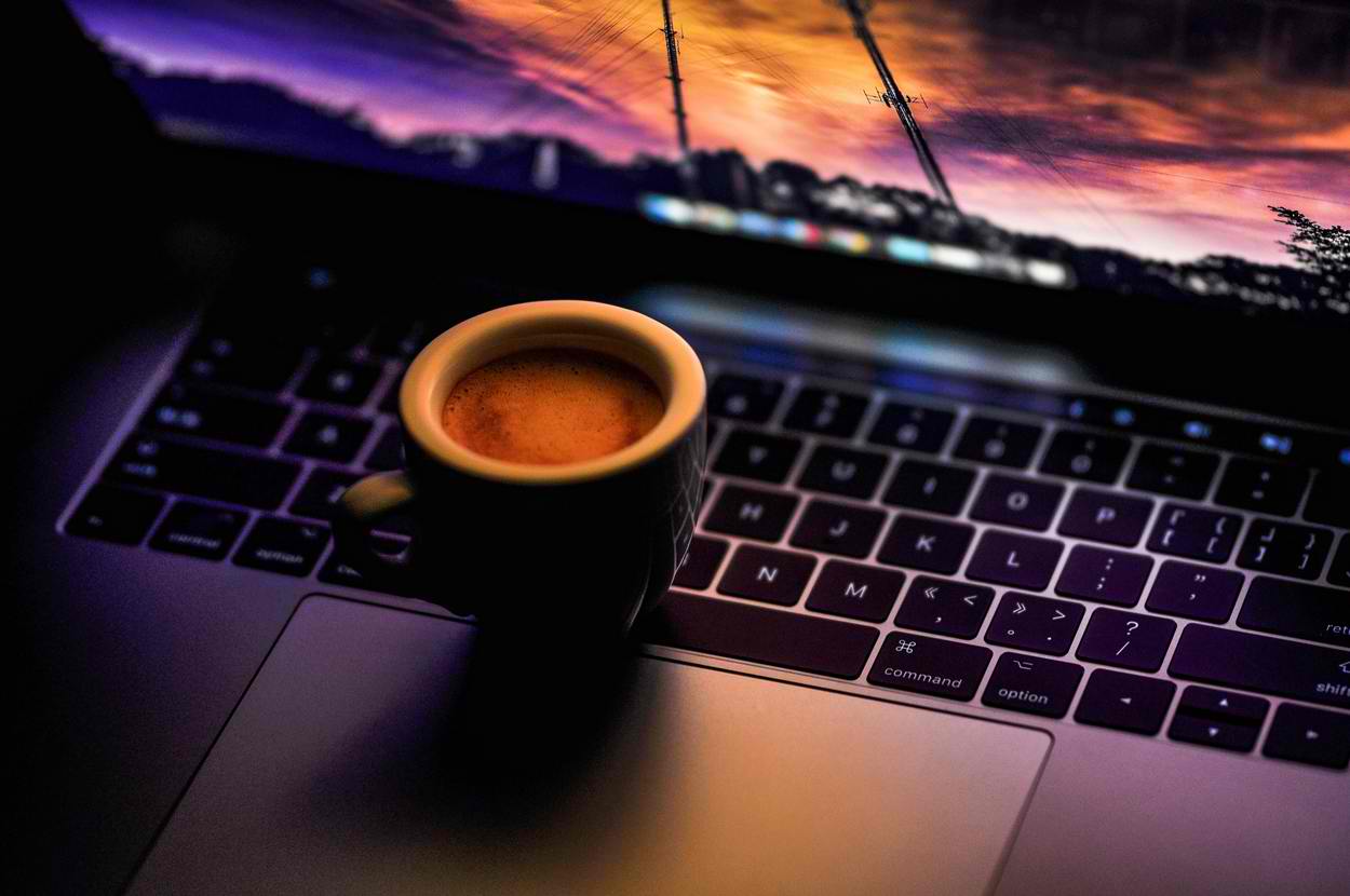 a cup of coffee on top of a laptop