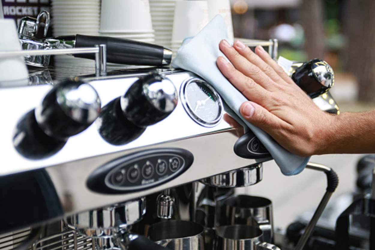 Barista man cleaning the espresso machine after working day